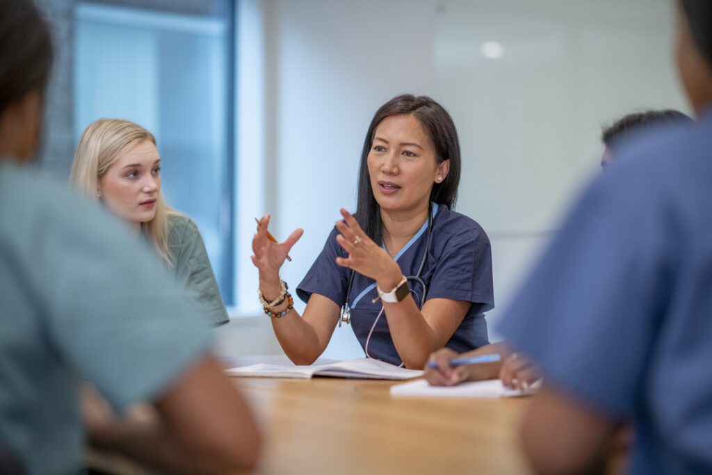 A small group of nurses sitting at a boardroom table having a meeting.